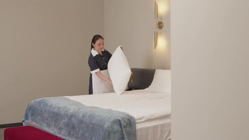 Latin Maid Making Bed in Hotel Room