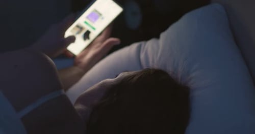 Woman Using Smartphone in Bed at Night