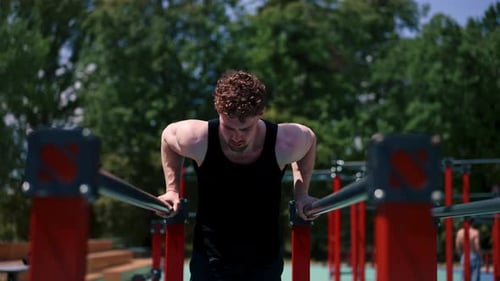 Man Doing Dips on Parallel Bars Outdoors