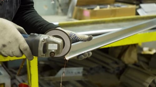 Factory Worker Using Angle Grinder to Clean and Polish Steel Profile