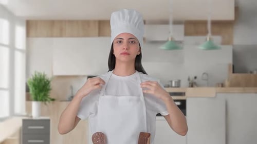 Woman Putting on Chef's Hat in Modern Kitchen