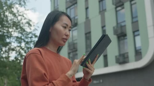 Shocked Asian Woman Reacting To Unexpected News On Tablet Outdoors