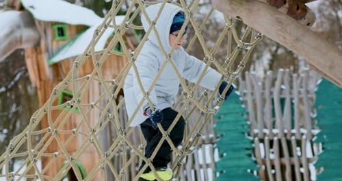 Child Climbing Rope Net in Winter Playground Adventure