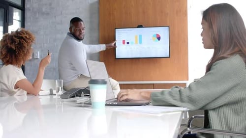 Diverse male and female colleagues using laptop and monitor at office meeting, slow motion