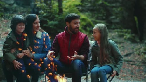 Close Up Family Sits Near Campfire on Autumn Children with Their Parents are Resting in the Woods