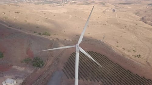 Aerial footage of Wind turbines spinning, in a mountain forest surrounding