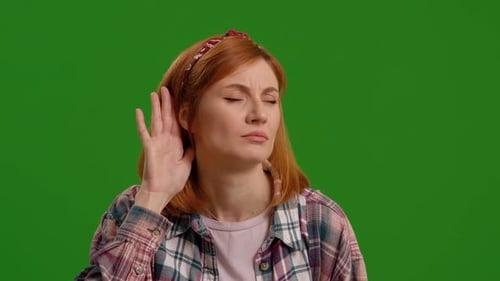 Woman, hand and ear for listening by green screen with confused face,