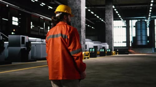 Engineer Walking Inside Factory Inspecting Heavy Machinery Along Production Line