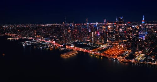 Flight over the dark area of the East River at night. Slow distancing from the cityscape of New York