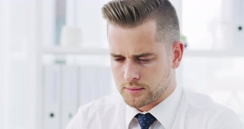 4k video footage of a young businessman suffering with a headache while working in an office