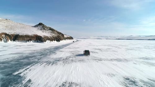 Aerial View on a Cars Driving on Cracked Ice of Baikal to the Famous Tourist Spot Winter Landscape