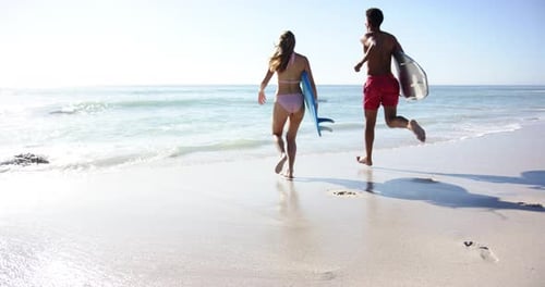 Young Caucasian woman and man are running along the beach with copy space