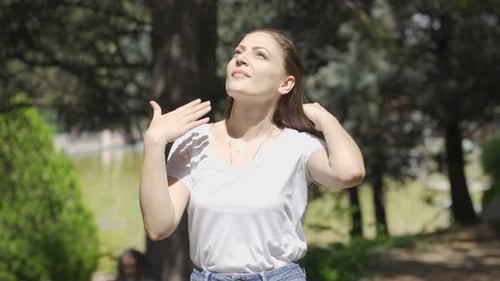 La femme suffoque à cause du soleil et de la chaleur qu'il fait dehors.