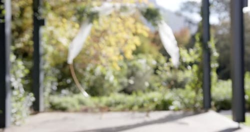 General view of wedding arch with decorations and flowers in sunny garden, copy space, slow motion