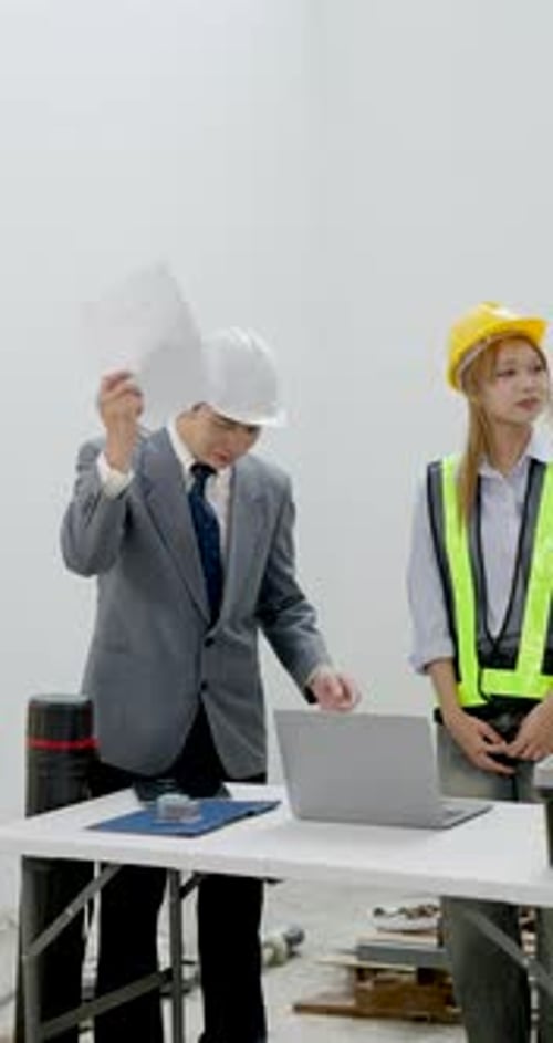 Asian male engineer and female contractor meet beside laptop table, reviewing building plan,