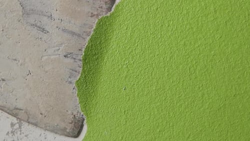 primer plano fijo de un hombre raspando pintura verde de una pared