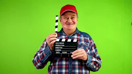 Amable y divertido hombre mayor aplaude en claqueta durante la producción de la película