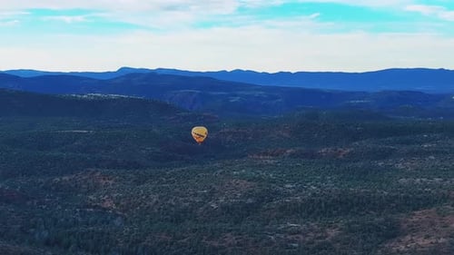 Colorful Hot Air Balloon At Sunrise Floats Above Lush Green Sedona Landscape In Arizona, USA. wide a
