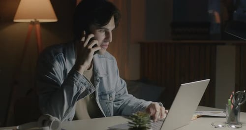 Successful Entrepreneur Discussing Business on Mobile Phone and Working with Laptop in Home Office
