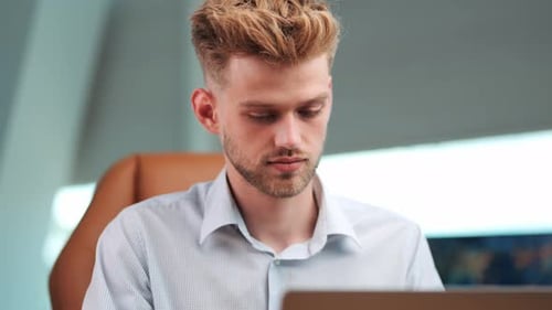 Focused Productivity: Young Businessman Concentrated on Notebook, Engaged in Writing