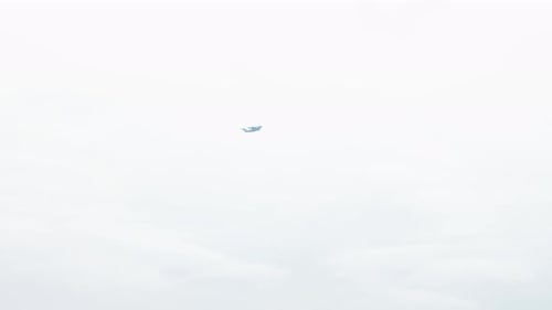 Distant View of Airplane Flying in Cloudy Sky