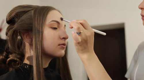 Woman Receives Makeup Application Indoors for Beauty Look