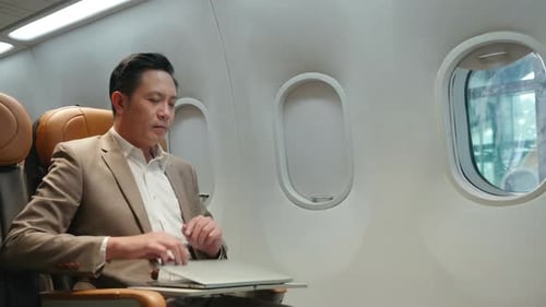 Man closes laptop and airplane window shade