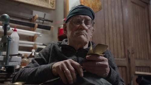 Elderly Male Master Works in His Workshop Restoring Furniture