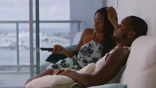 Young Couple Relaxing on Couch Eating Popcorn Indoors