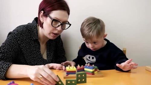 Kid with Special Needs and Teacher Playing with Developing Toys in Daycare Rehab Center