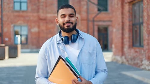 Smiling Student Holding Notebooks on Campus