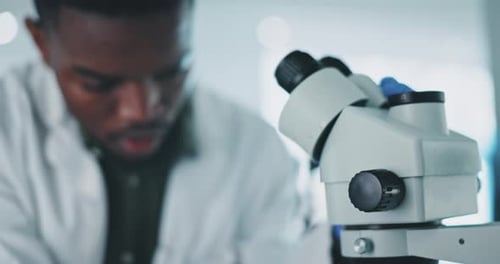 Young Adult Scientist Analyzing Sample Under Microscope
