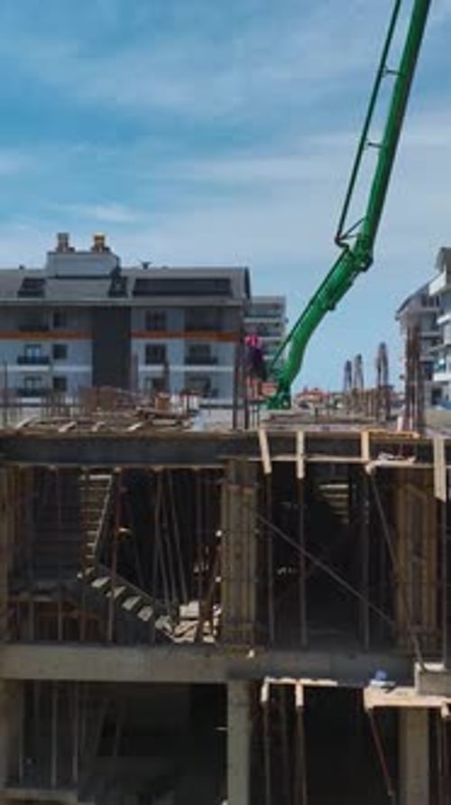 Vídeo vertical cerca de un edificio completo con trabajadores añadiendo vidrios y acabando balcones