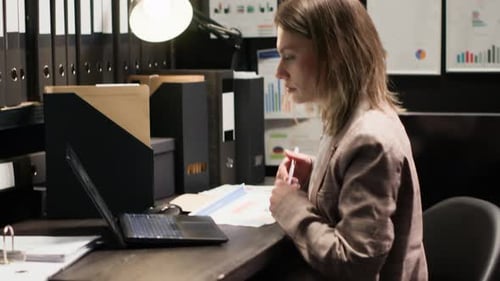 Businesswoman Working at Computer in Dim Office