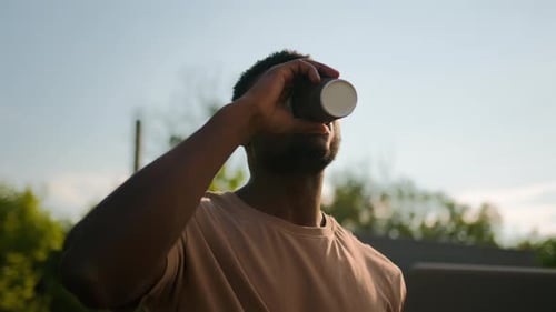 Young Man Works Outdoors with Laptop and Coffee