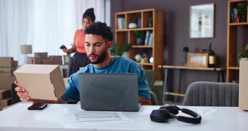 Man Working on Laptop with Cardboard Box