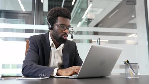 Man in Suit Typing at Laptop With Headset