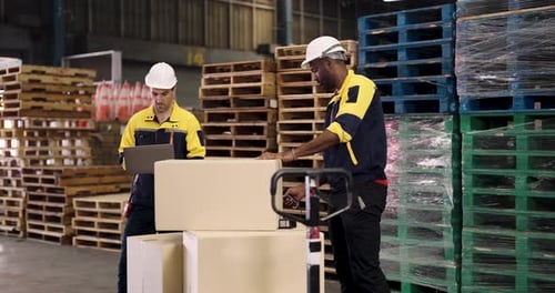 Multicultural male workers coordinating inside warehouse space using laptop and scanning system to c