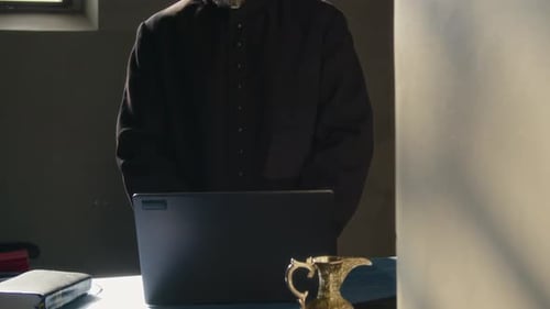 Man in Clerical Collar Stands at Desk