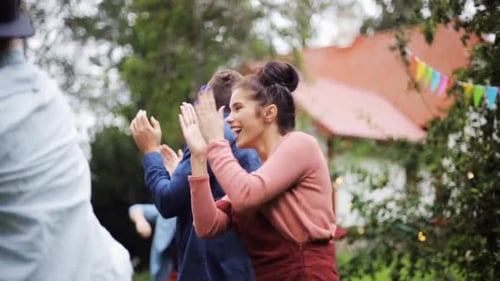 Happy friends dancing groovy music at summer garden party reunion