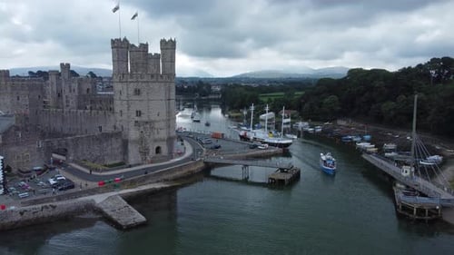 Ancient Caernarfon castle Welsh harbour town aerial view medieval waterfront landmark right orbit sl