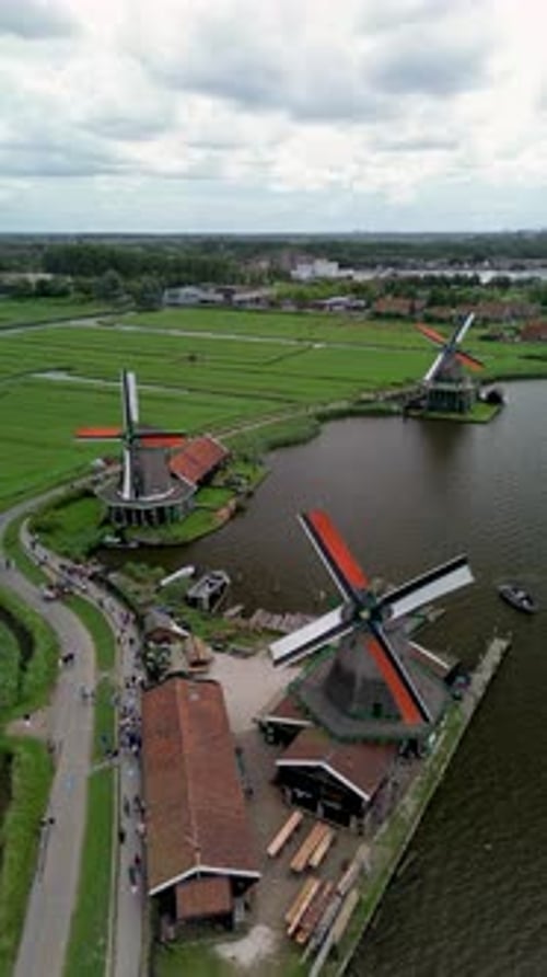 Vue par drone des moulins à vent hollandais traditionnels le long de la rivière, entourés de champs verts et de canaux