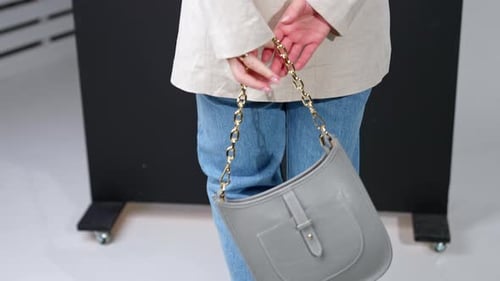 Woman Holding Stylish Grey Purse with Gold Chain