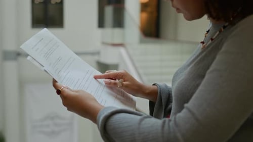 Black Female Manager Reading Document while Standing in Office Building