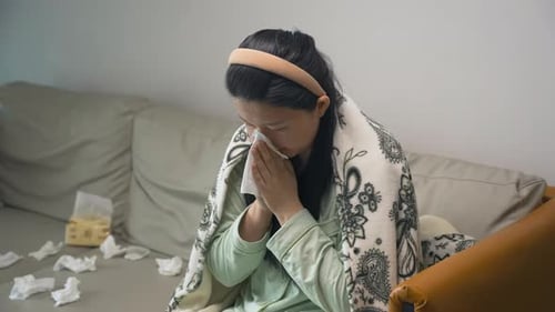 Femme malade qui tousse à la maison, éternue, se mouche dans un mouchoir en papier, est infectée par un virus