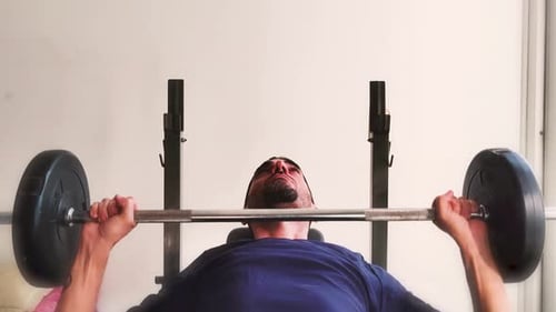 Man Lifts Barbell on Weight Bench