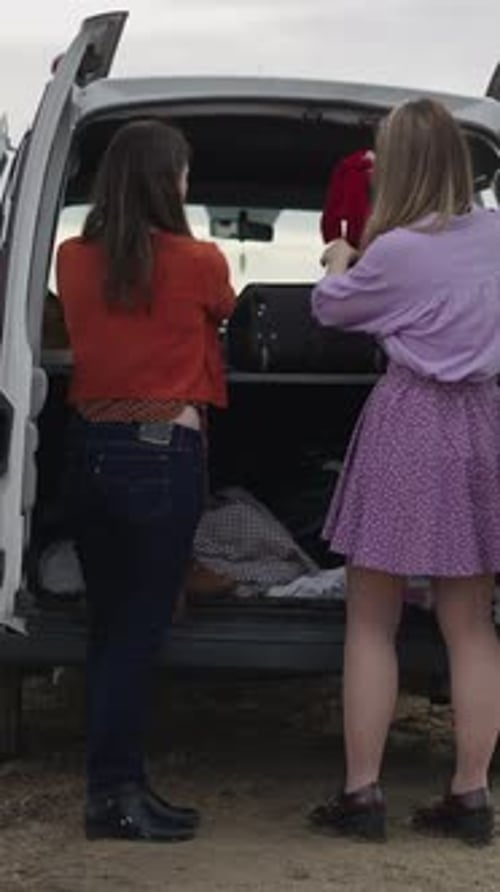 Em uma van, dois amigos escolhem roupas