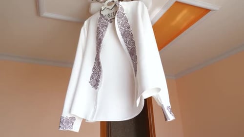 1. An der Lampe hängt eine weiße bestickte Herrenjacke.