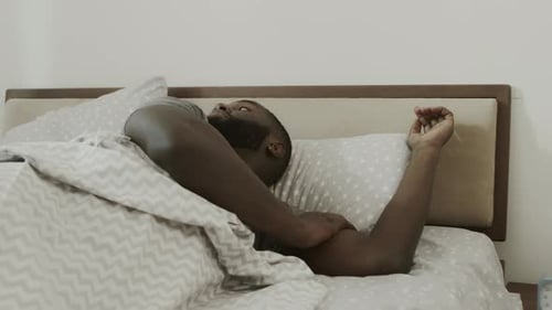 Man Waking up and Stretching in His Bed