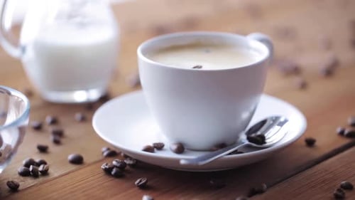 Coffee cup with milk and coffee beans on table
